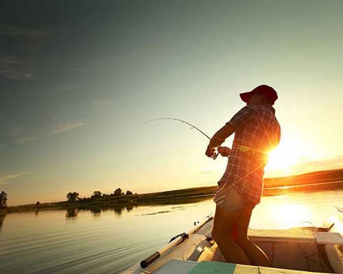 Fisherman reeling in a fish from a boat.